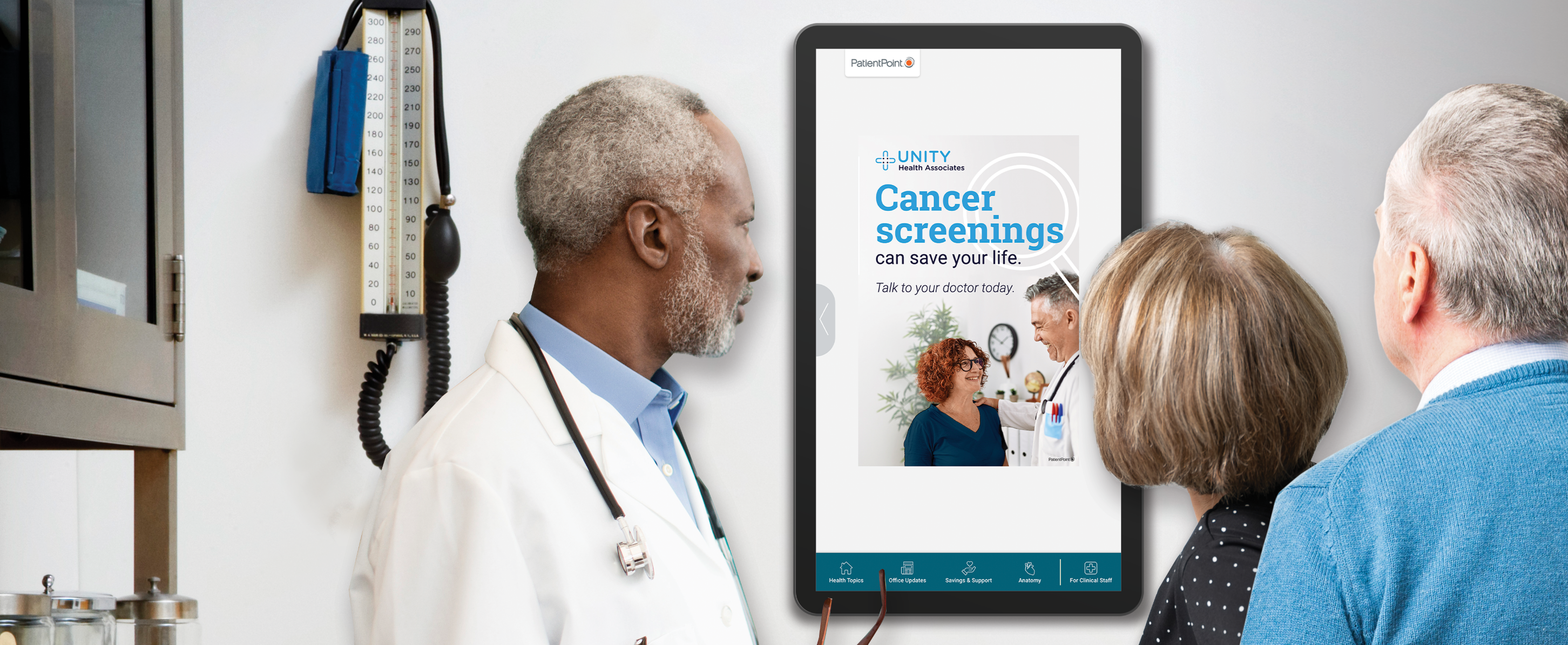 A provider and a patient viewing an exam room screen showing a cancer screening message